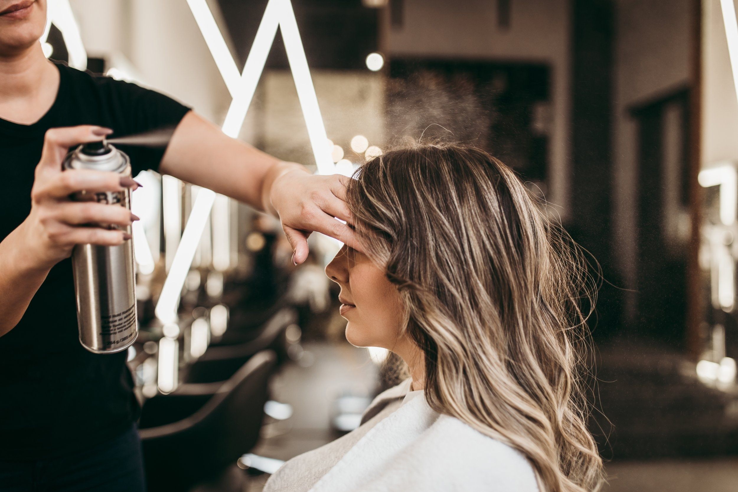 Stylist finishing a client's hair with hairspray