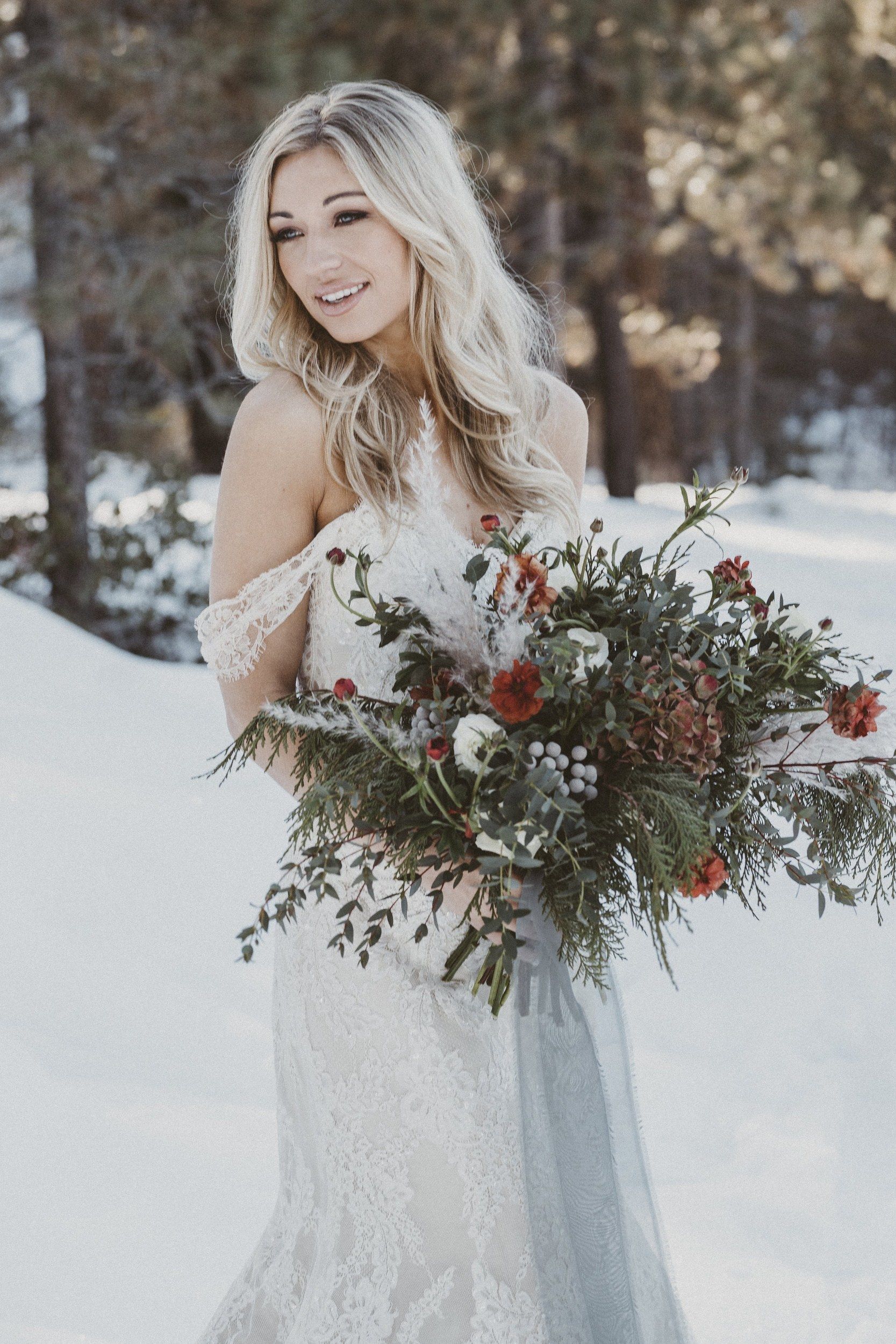 Bride with long waves and a bouquet in the snow