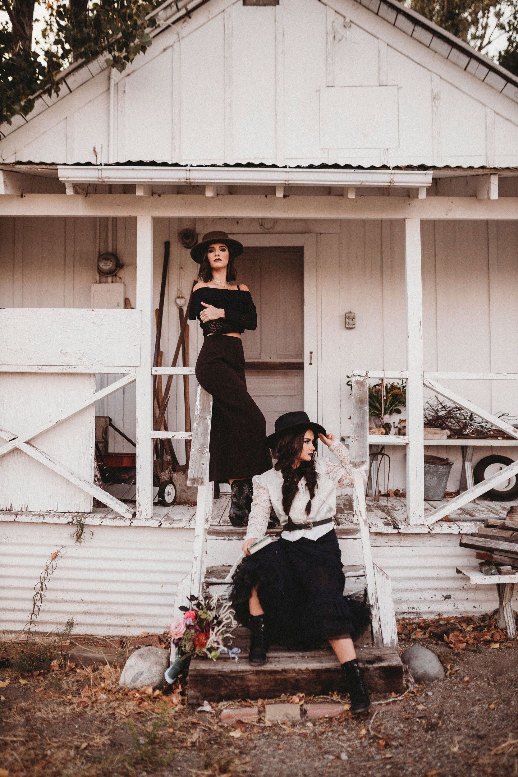 Two women in black on a farmhouse porch, Southern Gothic styled shoot